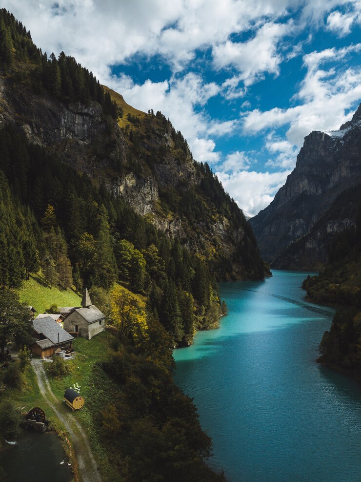 scenery-beautiful-river-mountains-small-houses-cloudy-sky_181624-4443