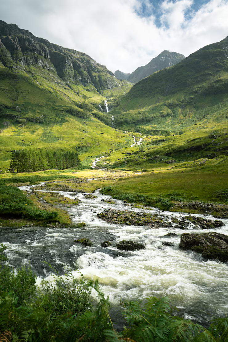 vertical-shot-river-surrounded-by-mountains-meadows-scotland_181624-27881