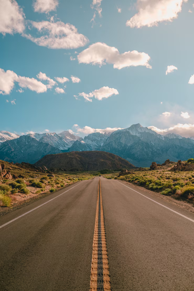 vertical-shot-road-with-magnificent-mountains-blue-sky-captured-california_181624-44891